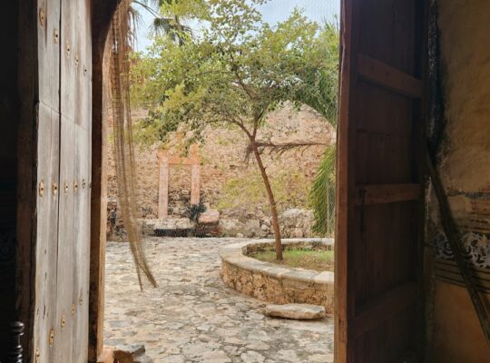 an open door leading to a courtyard with a hammock